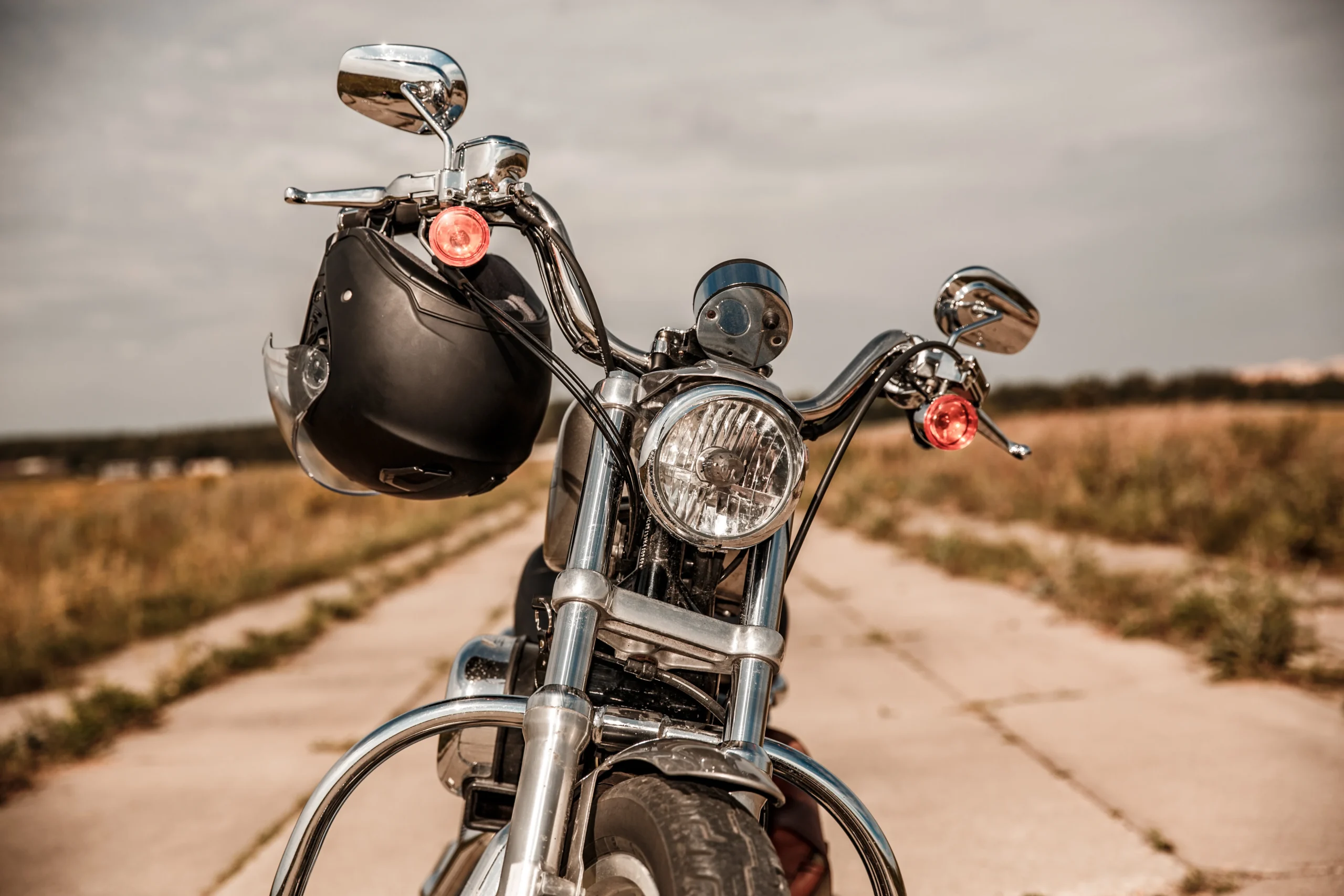 Motorcycle on the road with a helmet on the handlebars.