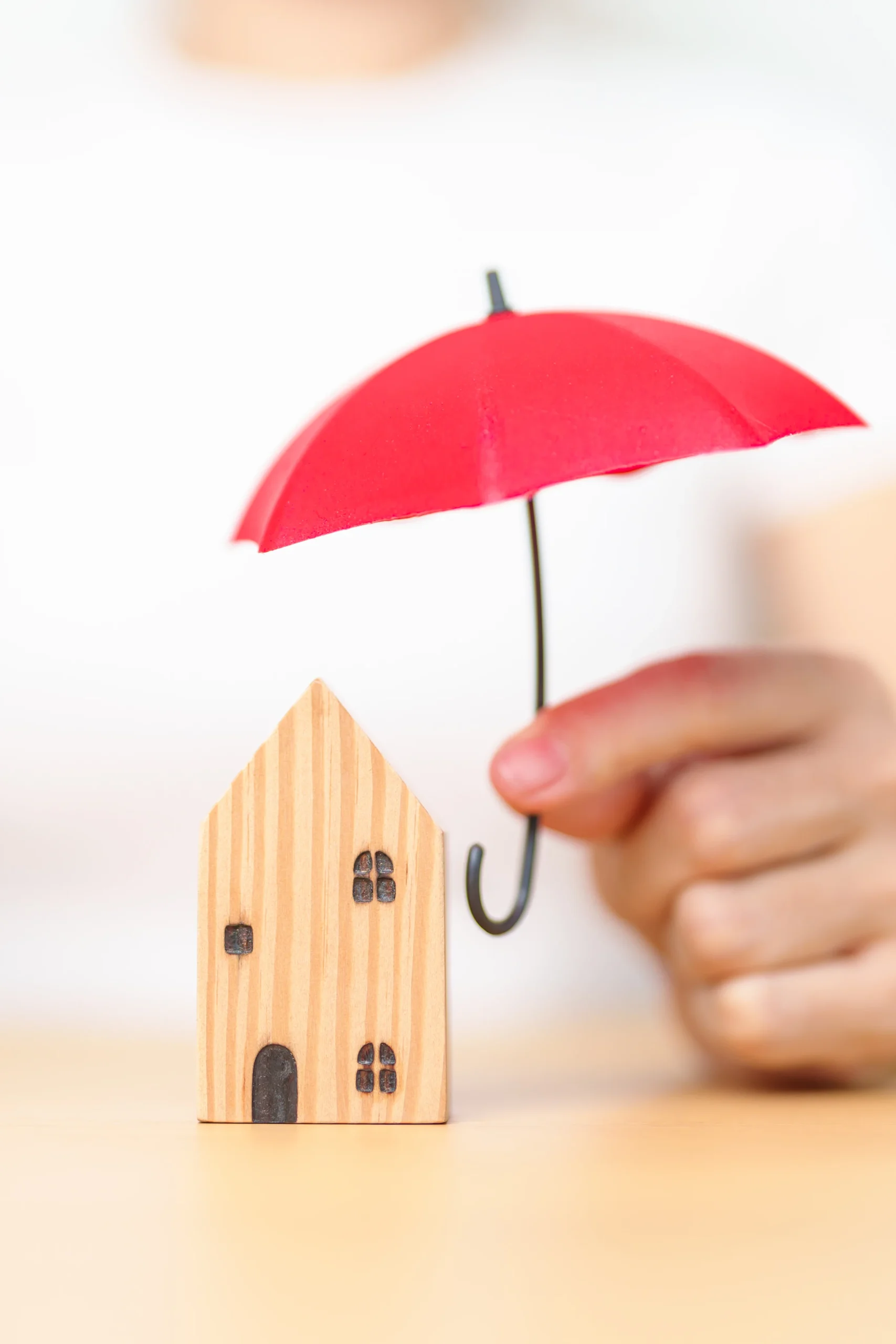 Businesswoman hand holding red Umbrella cover wooden Home model. real estate, insurance and property concepts Businesswoman hand holding red Umbrella cover wooden Home model. real estate, insurance and property concepts